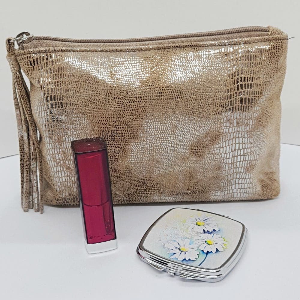 Handy mirror compact shown with makeup bag and lipstick