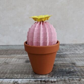 Pastel pink origami cactus plant with a yellow paper flower in a terracotta pot
