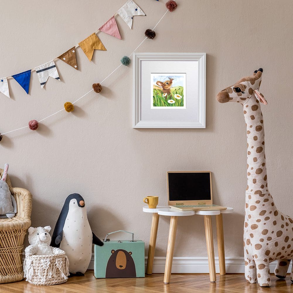 A picture of a sweet brown rabbit sitting amongst white daisies and green grasses with an inquisitive butterfly on his nose. The picture is displayed hanging on a nursery wall.