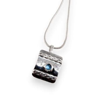 Sterling silver blue topaz pendant with woven detail on a white background