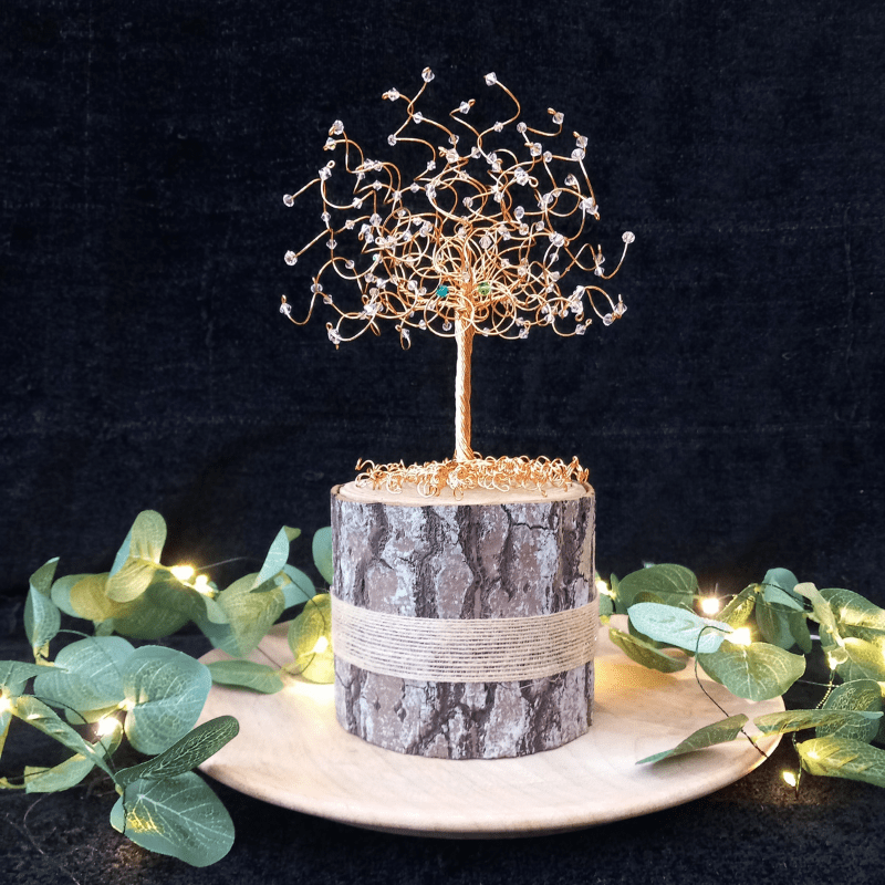 Gold wire and crystal tree sitting on a decorative log as a cake topper tree