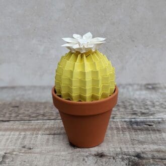 Pastel yellow paper cactus with a white origami flower in a terracotta pot