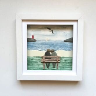 pebble couple on a wooden bench with sea view backdrop