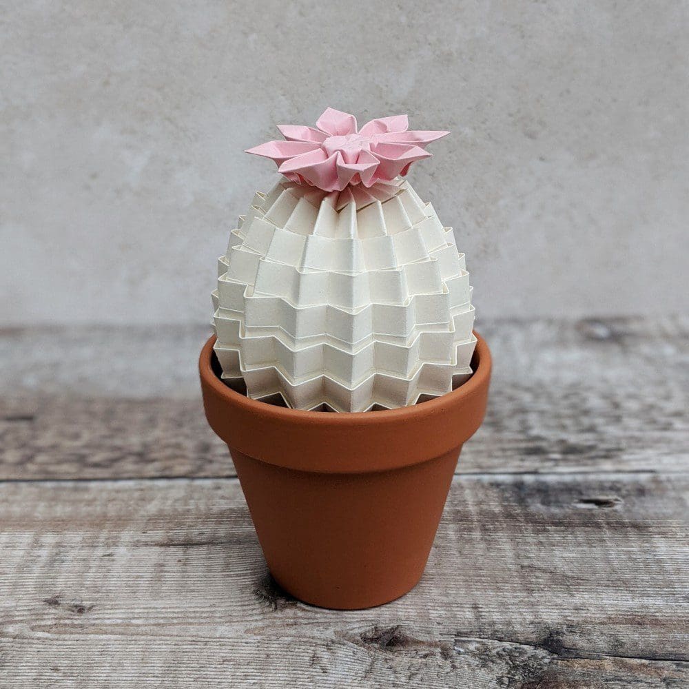 large white origami cactus plant with a pale pink flower in a terracotta pot
