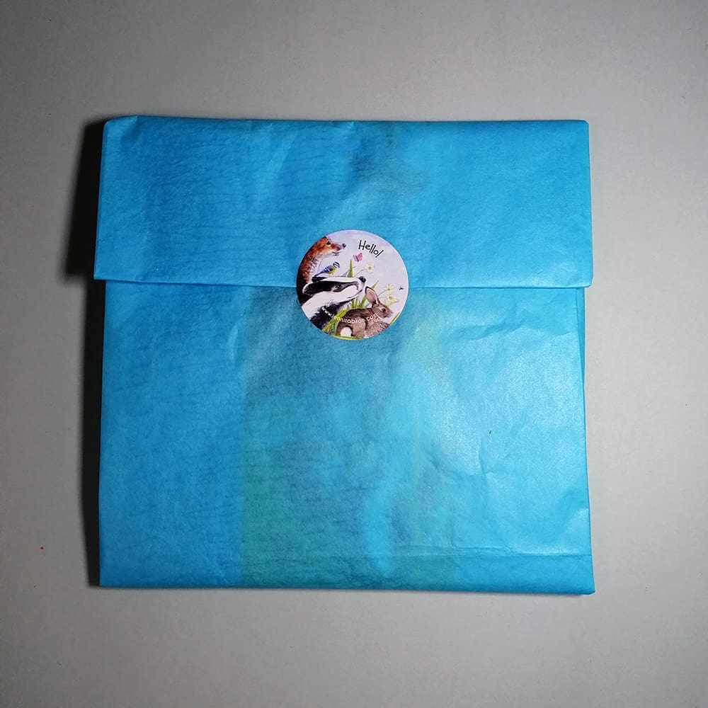 Three card set wrapped in tissue paper and sealed with a character sticker ready for sending.