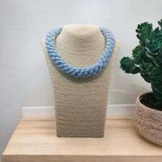 Baby Blue chunky necklace displaed on a bust model which is on a light wooden coutner top with a white background