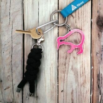 Black chunky knotted keyring made from recycled cotton cord and shown on a bunch of key that is displayed on a light wooden background.