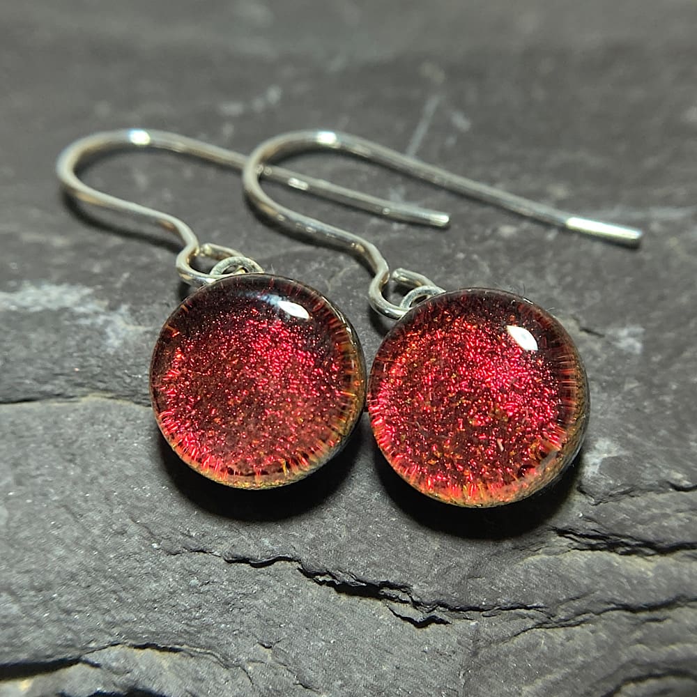 A pair of red gold fused dichroic glass drop earrings viewed from the front