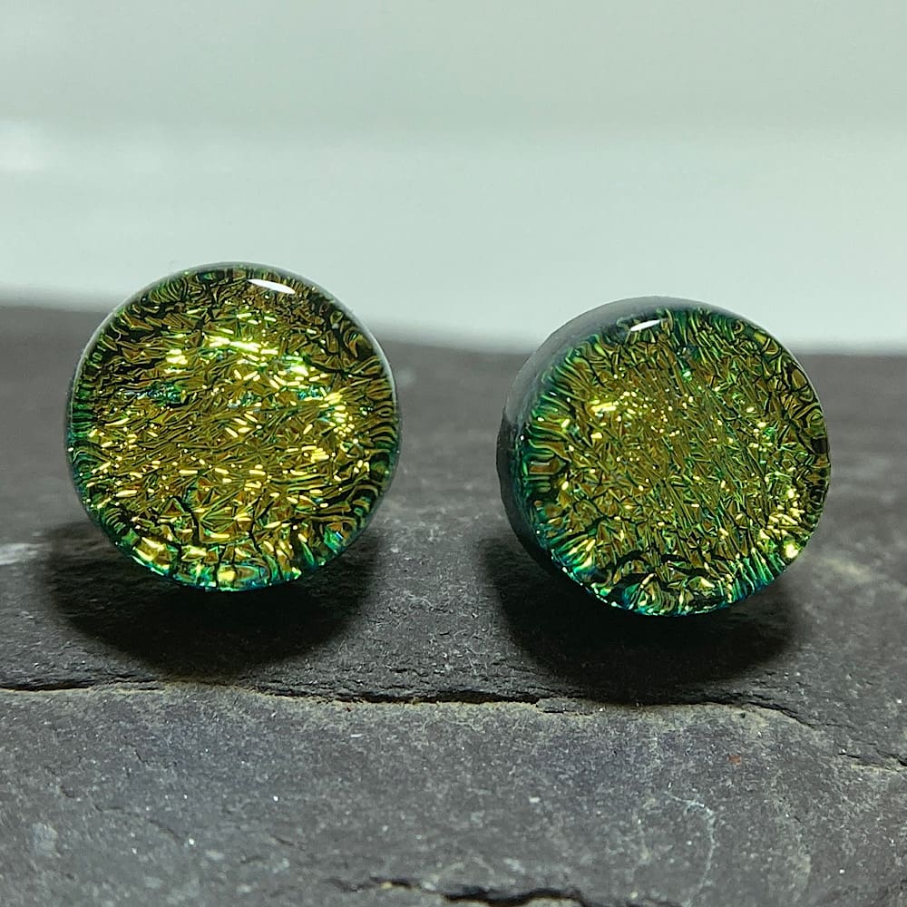 A pair of gold green fused dichroic glass stud earrings viewed from the front