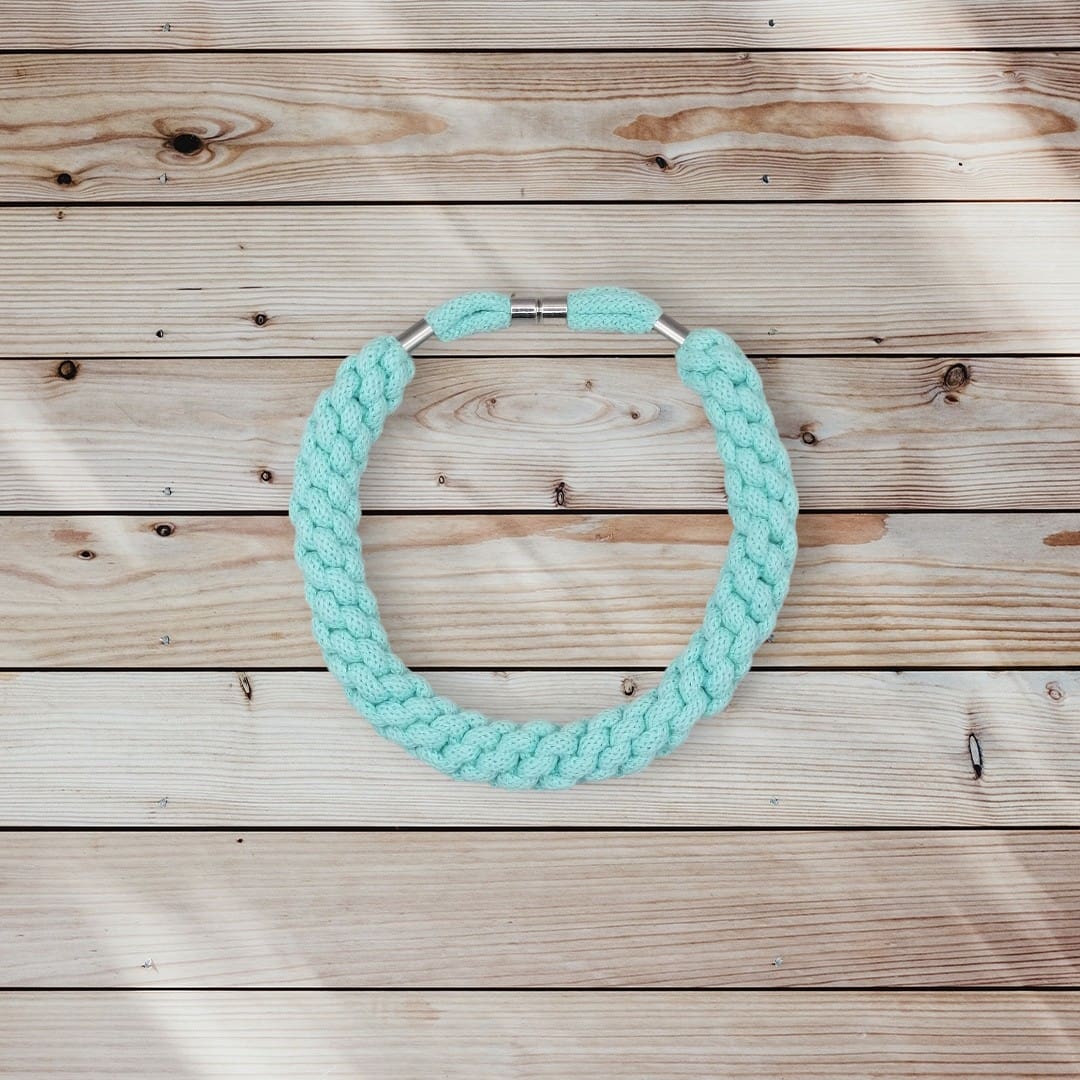 Flaylay view from above os chunky aqua rope necklace on pale wood background