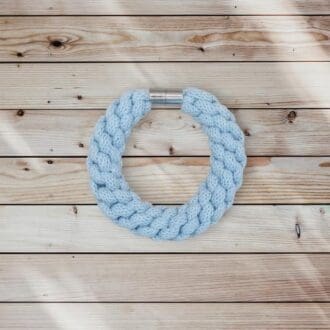 Chunky Baby Blue Bracelet that is made from knotted recycled cotton cord and finished with a magenetic claps that is viewed from above and laid on a plain wooden background