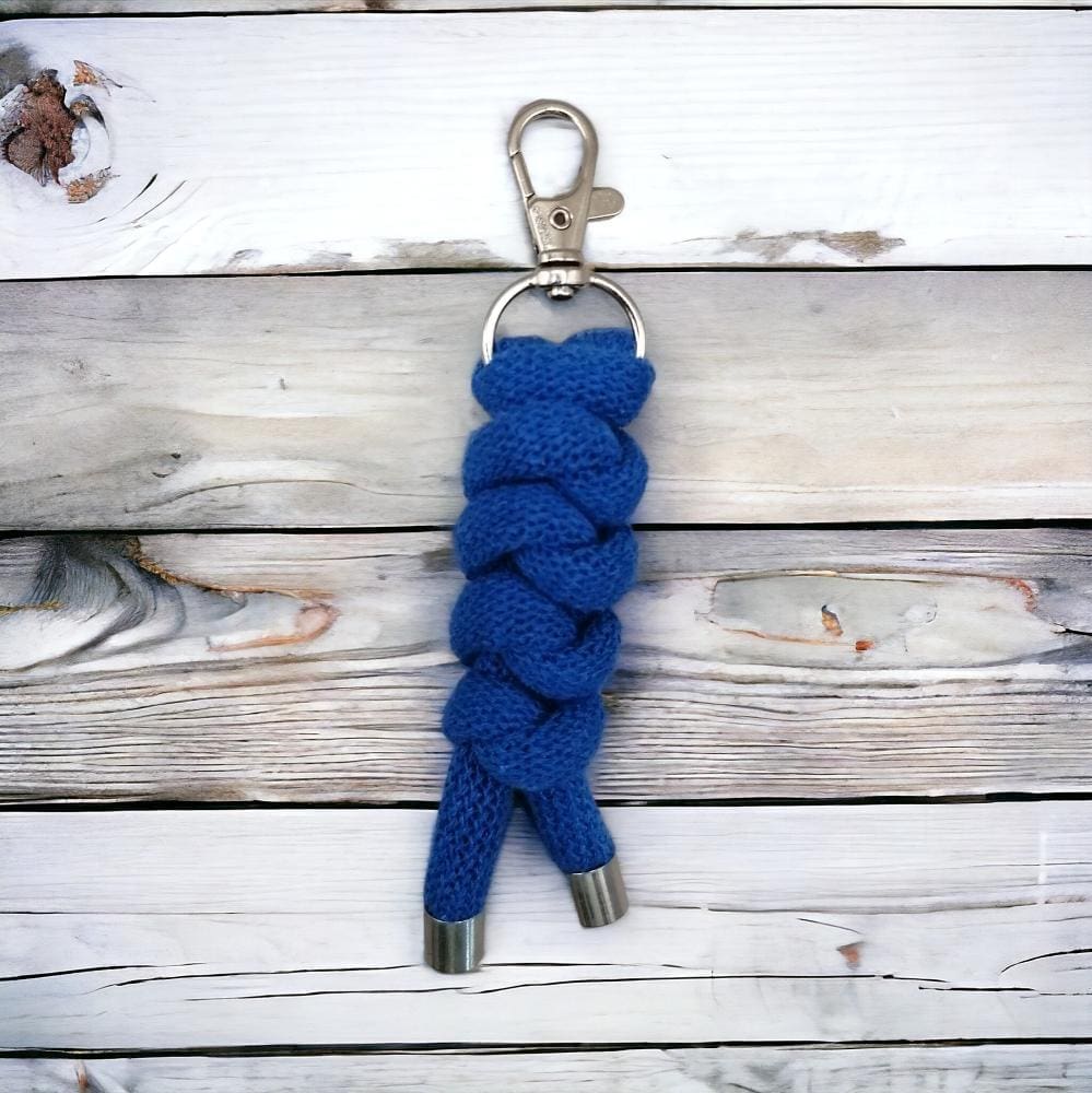 Close up of chunky blue knotted cord keyring shown on a light wood background.