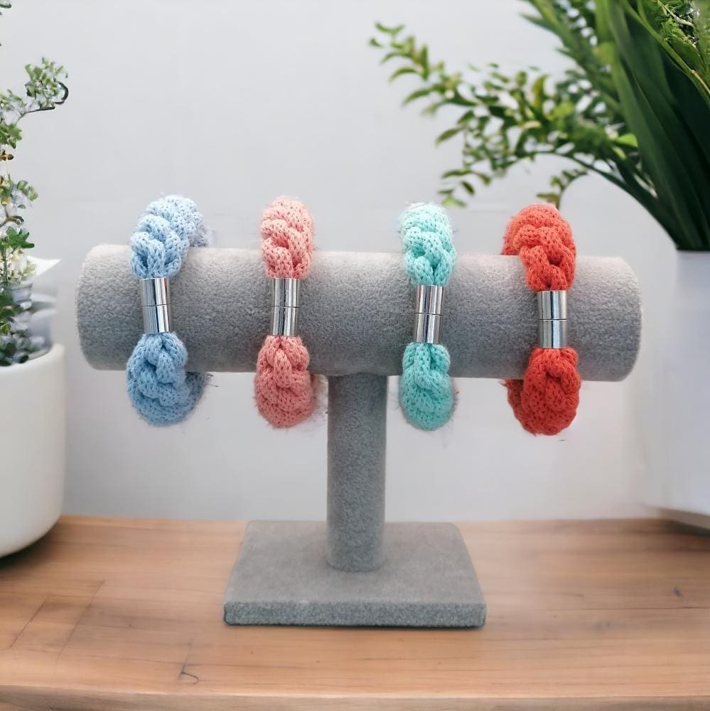 Group of chunky knotted bracelets displayed on a bracelet stand against a plain background.