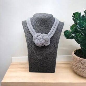 Chunky Grey rope necklace with central knot feature displayed on a a model bust on a light wooden worktop with a white background.