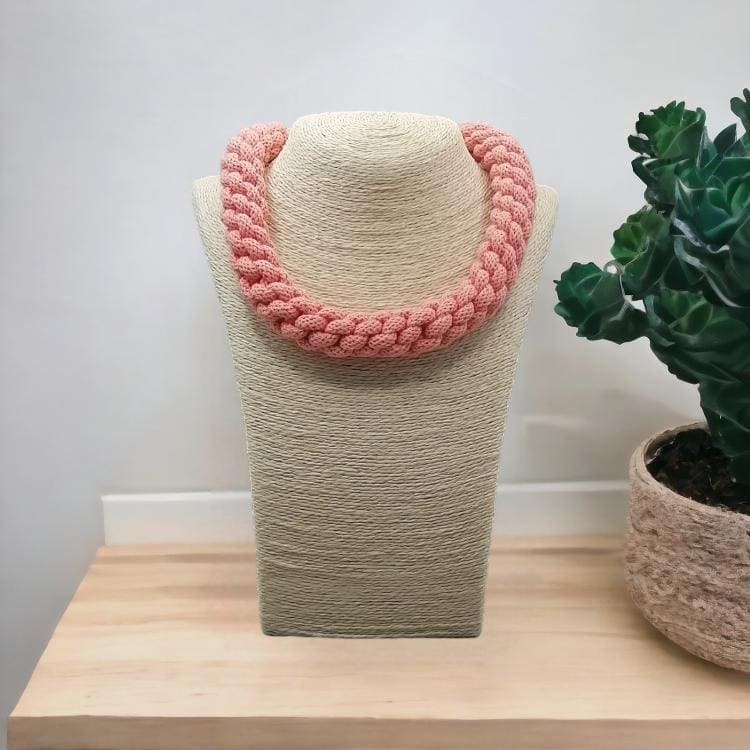 Peach chunky rope statement necklace displayed on a bust upon a light wooden counter top with a white backgroun