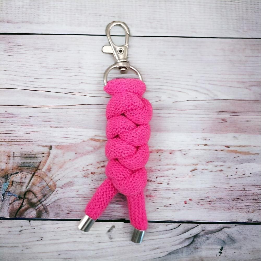 CLose up of chunky pink keyring made from knotted recycled cotton cord displayed on a light wooden background.