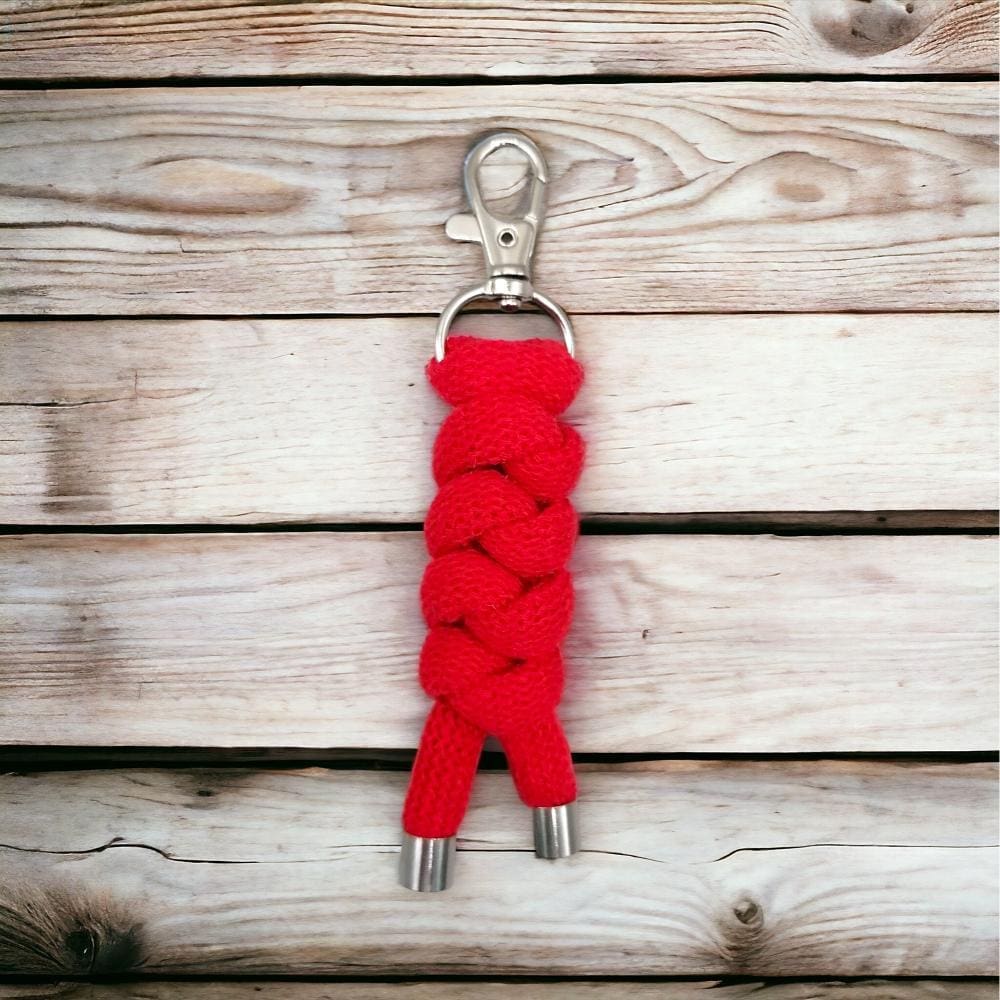 Close up of chunky red knotted rope keyring displayed on a light wooden background.