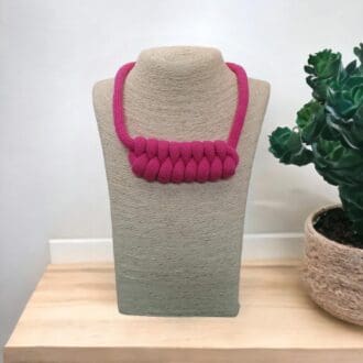 Chunky pink rope necklace on pale model stand with a pale background