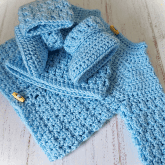 crochet baby gift set including cardigan, hat and booties in a pastel blue. This is made in size 0-3 months. The cardigan fastens with wooden toggle buttons. This set is ready-to-ship.