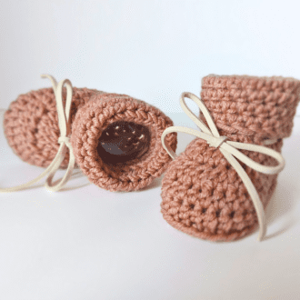 A pair of 100% merino wool baby booties, the ones pictures are in the shade of desert rose, they come with a faux leather bow and can be flat packed or boxed