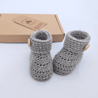A luxury pair of baby booties made in 100% merino wool, picutred are in shade Greige, which are made from the sole up with a folded cuff finished with a handmade with love wooden button. Available to order in sizes newborn, 0-3 and 3-6 months