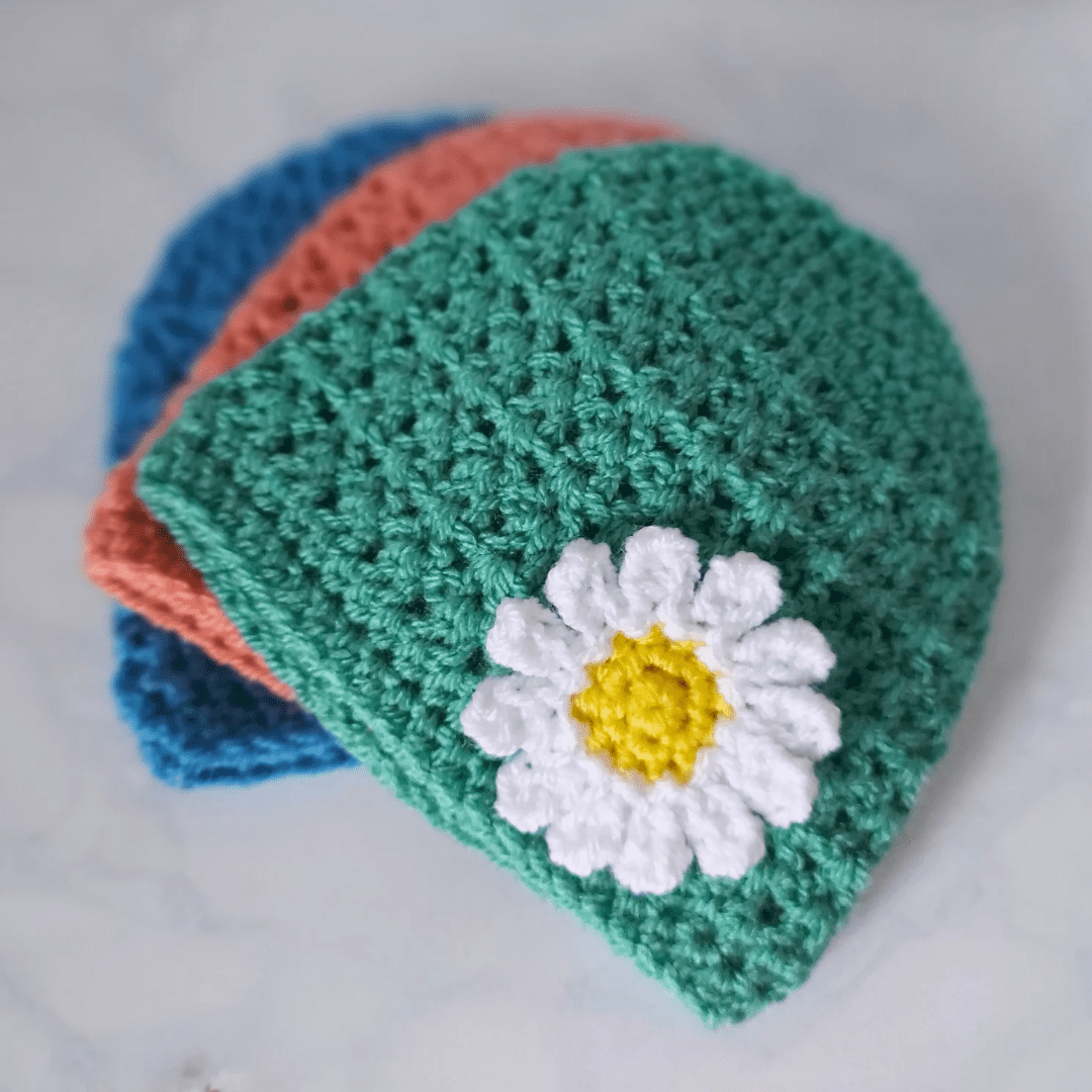 crochet baby beanie hats, made with 'v' stitch which gives texture yo the pattern. a handmade daisy is attached to the hat. it is made in one piece so no itchy seams. sizes are newborn up to 2 years with a variety of colours to choose from