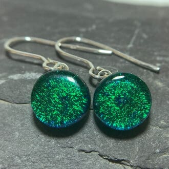A pair of emerald green fused dichroic glass stud earrings viewed from the front