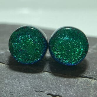 A pair of emerald green fused dichroic glass stud earrings viewed from the front