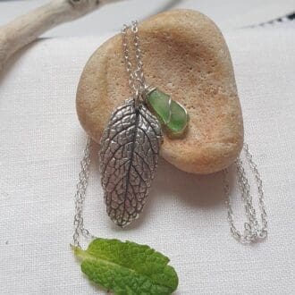 silver mint leaf & mint sea glass necklace on sterling silver chain nestled amongst some mint leaves