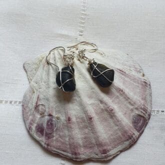 a 'pair' of rare pirate sea glass earrings, wrapped in fine silver wire displayed on a large shell.