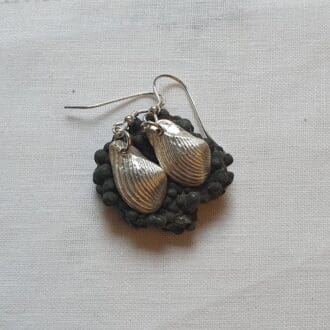 A pair of fine silver fossil shell earrings displayed on a black pyrite rock