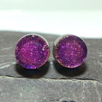 A pair of magenta pink fused dichroic glass stud earrings viewed from the front