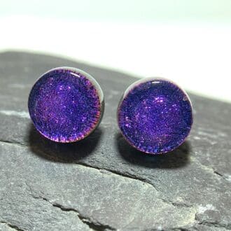 A pair of magenta blue fused dichroic glass stud earrings viewed from the front