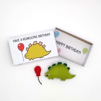 A cute handmade happy dinosaur with a balloon magnets in an illustrated matchbox birthday gift
