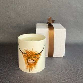 Highland Cow handpainted image onto scented candle on grey background.