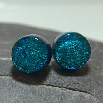 A pair of peacock blue fused dichroic glass stud earrings viewed from the front