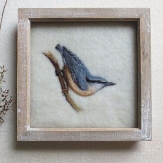 Needle felted wool painting of a Nuthatch songbird on a cream background and in a shabby-chic natural wood frame.