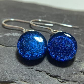 A pair of cobalt blue fused dichroic glass drop earrings viewed from the front