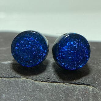 A pair of cobalt blue fused dichroic glass stud earrings viewed from the front