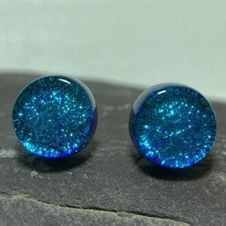 A pair of sky blue fused dichroic glass stud earrings viewed from the front