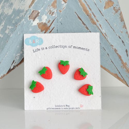 A set of five miniature clay strawberry fridge magnets set on seed paper backing