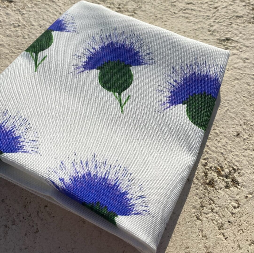 White 100% cotton tea towel printed with repeated thistle pattern