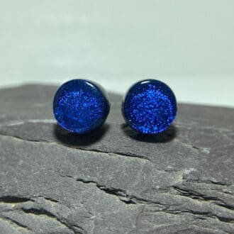 A pair of violet fused dichroic glass stud earrings viewed from the front