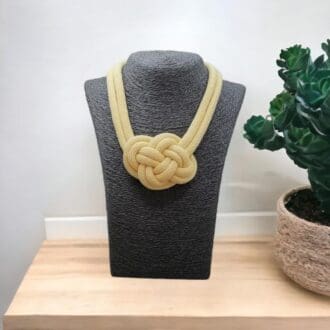 Chunky Yellow Necklace with large knot feature displayed on a dark grey model bust that is sat on a light wooden counter top with a white background.