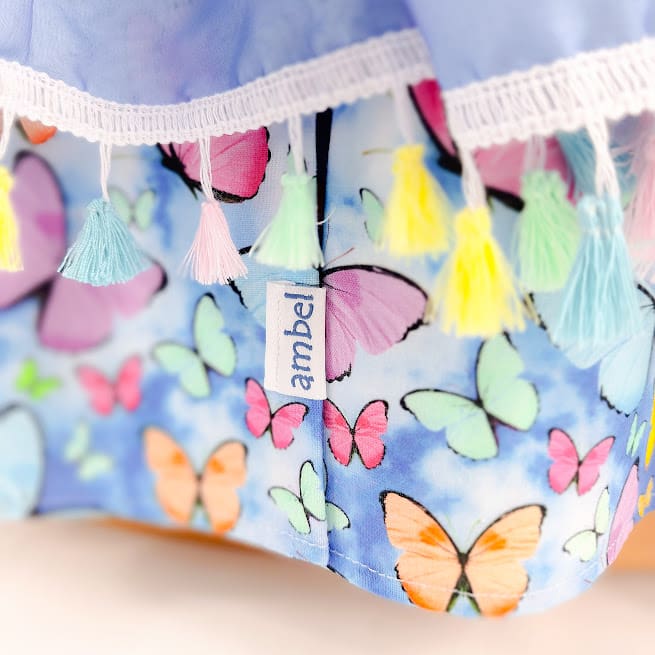 Close up of the butterfly themed fabric and pastel tassel canopy on Ambel Crafts dolls cot.