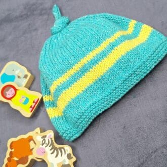 A childs blue and yellow striped knitted hat sits amongst some discarded toys.