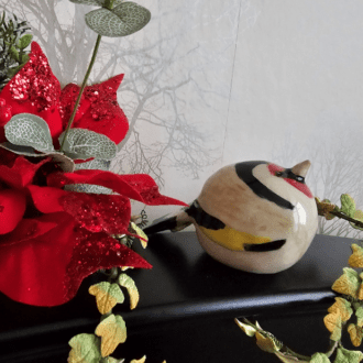Ceramic goldfinch on decorative background