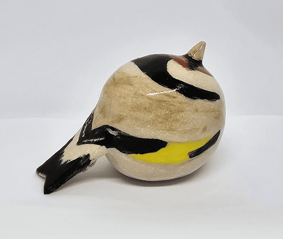 Side view of ceramic goldfinch on white background