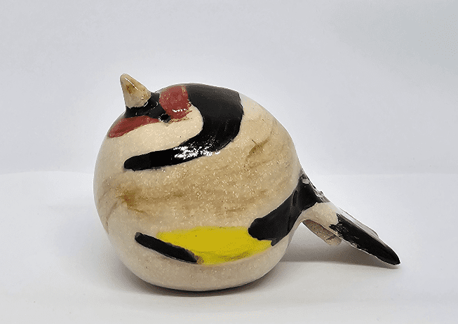 Side view of ceramic goldfinch on white background