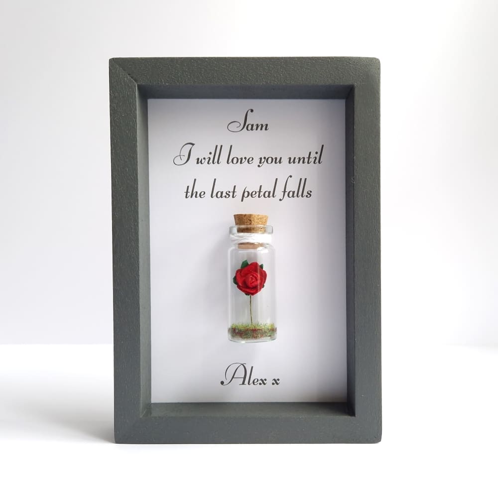 Small grey frame with a personalised quote and a mini glass bottle containing a paper rose.